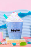 Ice cream with whipped cream and sprinkles in a blue cup on a colorful background