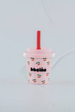 Pink tumbler with cherry design and straw on a light gray background