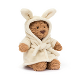 Teddy bear wearing a cream robe on a white background