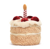 Plush toy resembling a birthday cake with red berries and a candle on a white background
