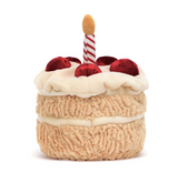 Plush toy resembling a birthday cake with red berries and a candle on a white background