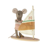 A small plush mouse figurine wearing a pink dress and holding a wooden sailboat with a cream, tan, and green striped sail. The sail features the number 20.
