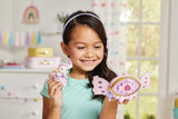Young girl holding a pink toy with a heart design in a room with colorful decorations.