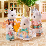Four toy cats in pastel outfits standing on a patterned surface with a blurred indoor background.