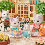 Four cat-themed figurines in a miniature outdoor setting with a house in the background.