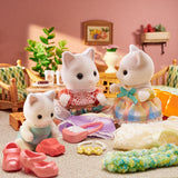 Three toy cats with accessories on a table in a room setting