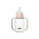 A clear plastic baby bottle with beige silicone handles and a beige collar, featuring a clear spout and the brand name 'BIBS' printed in black on the front, set against a plain white background.