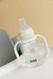 BIBS baby bottle with white cap on a light surface with a beige background