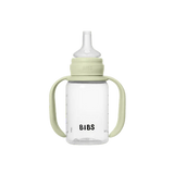 Clear baby bottle with green handle and lid on a white background